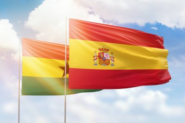Sunny blue sky and flags of spain and ghana
