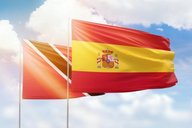 Sunny blue sky and flags of spain and trinidad and tobago