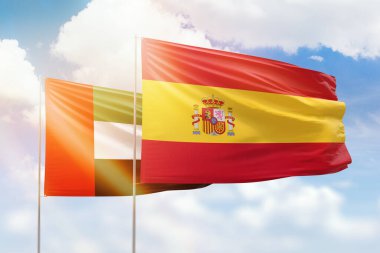 Sunny blue sky and flags of spain and uae