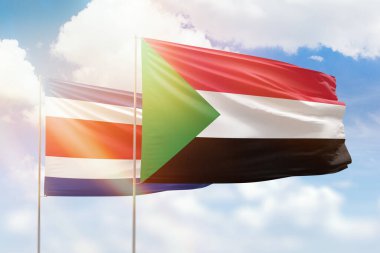Sunny blue sky and flags of sudan and costa rica