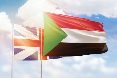 Sunny blue sky and flags of sudan and great britain
