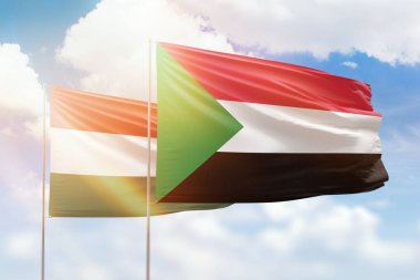 Sunny blue sky and flags of sudan and hungary