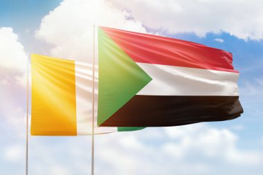 Sunny blue sky and flags of sudan and ivory coast