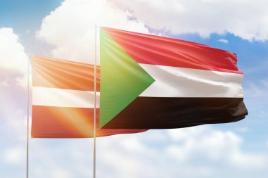 Sunny blue sky and flags of sudan and latvia
