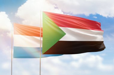 Sunny blue sky and flags of sudan and luxembourg