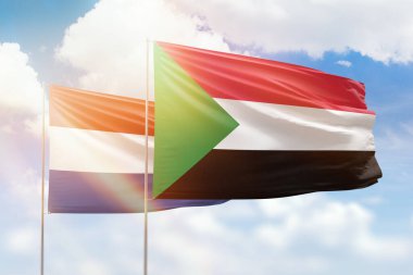 Sunny blue sky and flags of sudan and netherlands