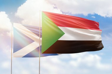 Sunny blue sky and flags of sudan and scotland