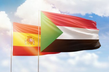 Sunny blue sky and flags of sudan and spain
