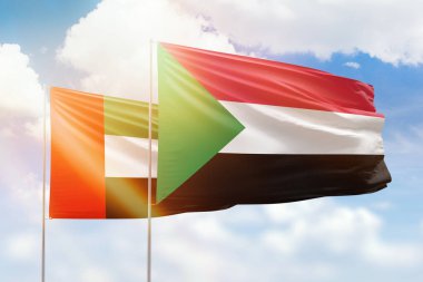 Sunny blue sky and flags of sudan and uae