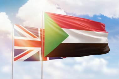 Sunny blue sky and flags of sudan and united kingdom