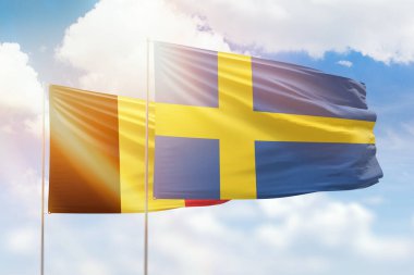 Sunny blue sky and flags of sweden and belgium