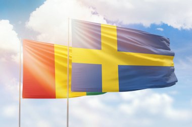 Sunny blue sky and flags of sweden and guinea