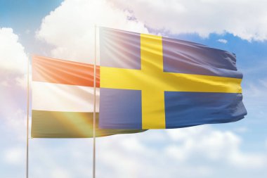 Sunny blue sky and flags of sweden and hungary