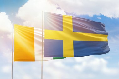 Sunny blue sky and flags of sweden and ivory coast