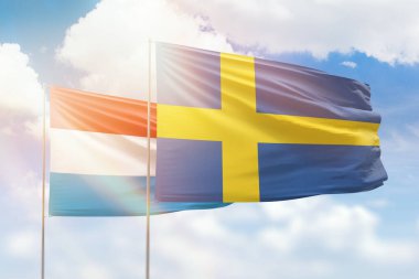 Sunny blue sky and flags of sweden and luxembourg