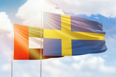 Sunny blue sky and flags of sweden and uae