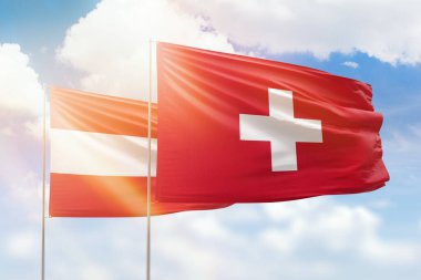 Sunny blue sky and flags of switzerland and austria