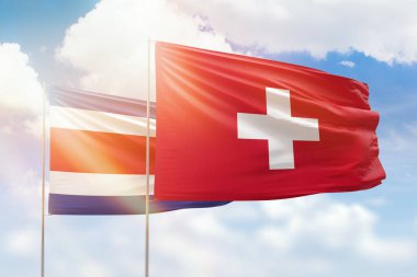 Sunny blue sky and flags of switzerland and costa rica