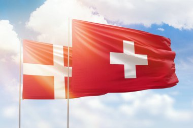 Sunny blue sky and flags of switzerland and denmark