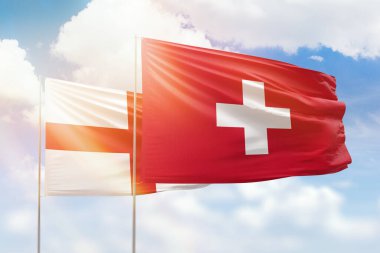 Sunny blue sky and flags of switzerland and england