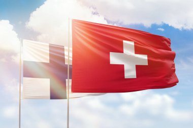 Sunny blue sky and flags of switzerland and finland