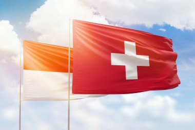 Sunny blue sky and flags of switzerland and indonesia