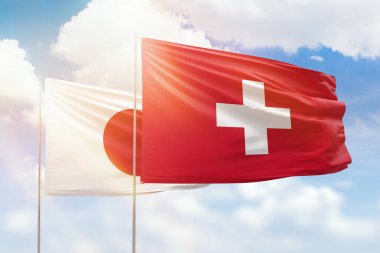 Sunny blue sky and flags of switzerland and japan