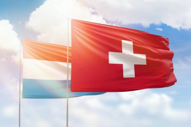 Sunny blue sky and flags of switzerland and luxembourg