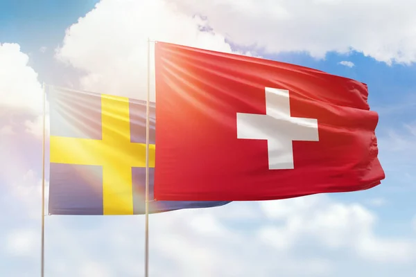 Sunny blue sky and flags of switzerland and sweden