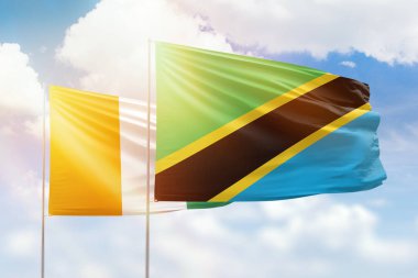 Sunny blue sky and flags of tanzania and ivory coast
