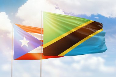 Sunny blue sky and flags of tanzania and puerto rico