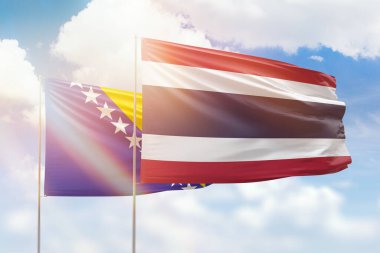 Sunny blue sky and flags of thailand and bosnia