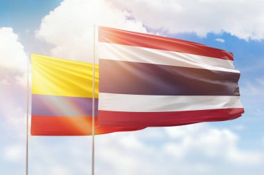 Sunny blue sky and flags of thailand and colombia