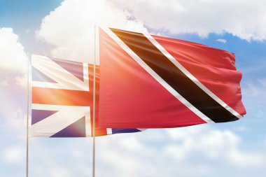 Sunny blue sky and flags of trinidad and tobago and great britain