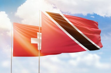 Sunny blue sky and flags of trinidad and tobago and switzerland