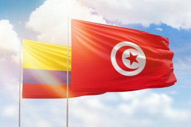 Sunny blue sky and flags of tunisia and colombia
