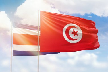 Sunny blue sky and flags of tunisia and costa rica