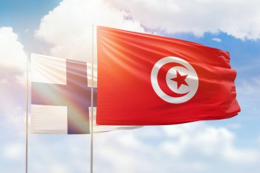 Sunny blue sky and flags of tunisia and finland
