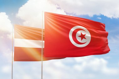 Sunny blue sky and flags of tunisia and latvia