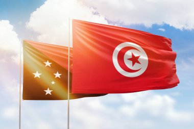 Sunny blue sky and flags of tunisia and papua new guinea