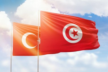 Sunny blue sky and flags of tunisia and turkey