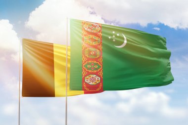 Sunny blue sky and flags of turkmenistan and belgium