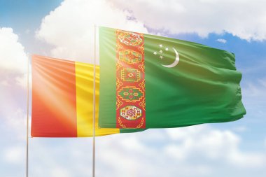 Sunny blue sky and flags of turkmenistan and guinea