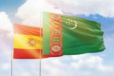 Sunny blue sky and flags of turkmenistan and spain