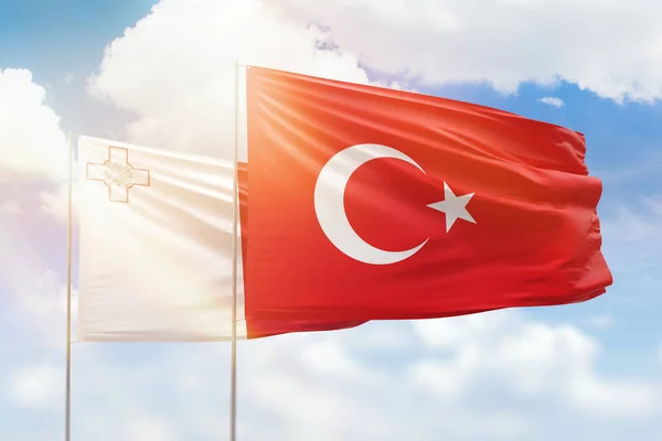 Sunny blue sky and flags of turkey and malta