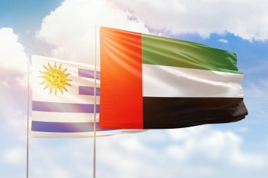Sunny blue sky and flags of united arab emirates and uruguay