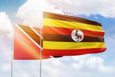 Sunny blue sky and flags of uganda and trinidad and tobago