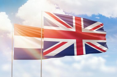 Sunny blue sky and flags of united kingdom and netherlands