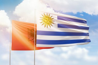 Sunny blue sky and flags of uruguay and albania