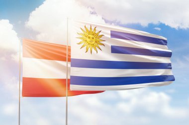 Sunny blue sky and flags of uruguay and austria